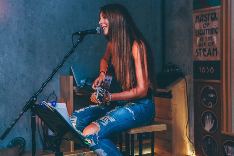 woman singing and playing an acoustic guitar